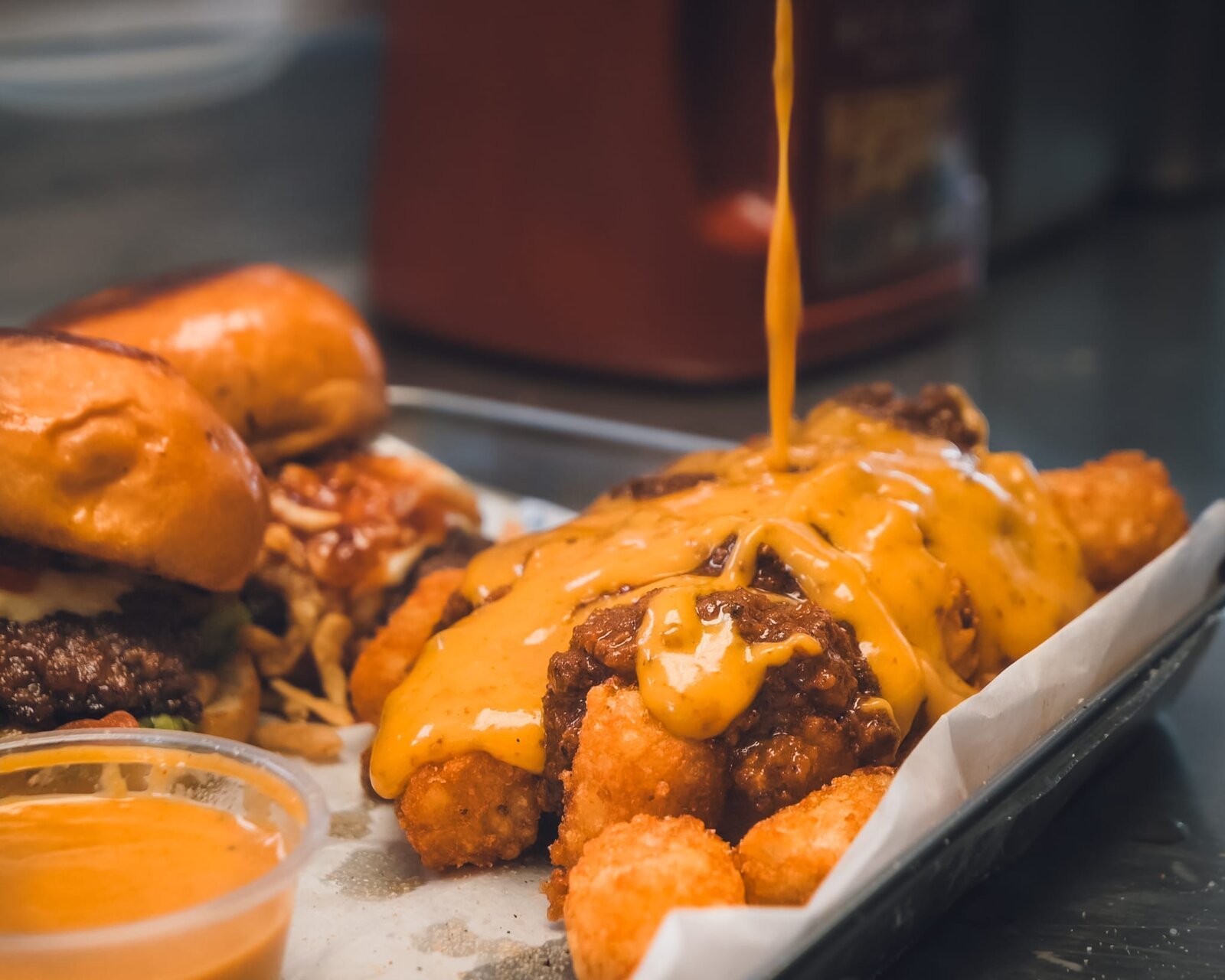 Gold sauce being poured over loaded fries and tots